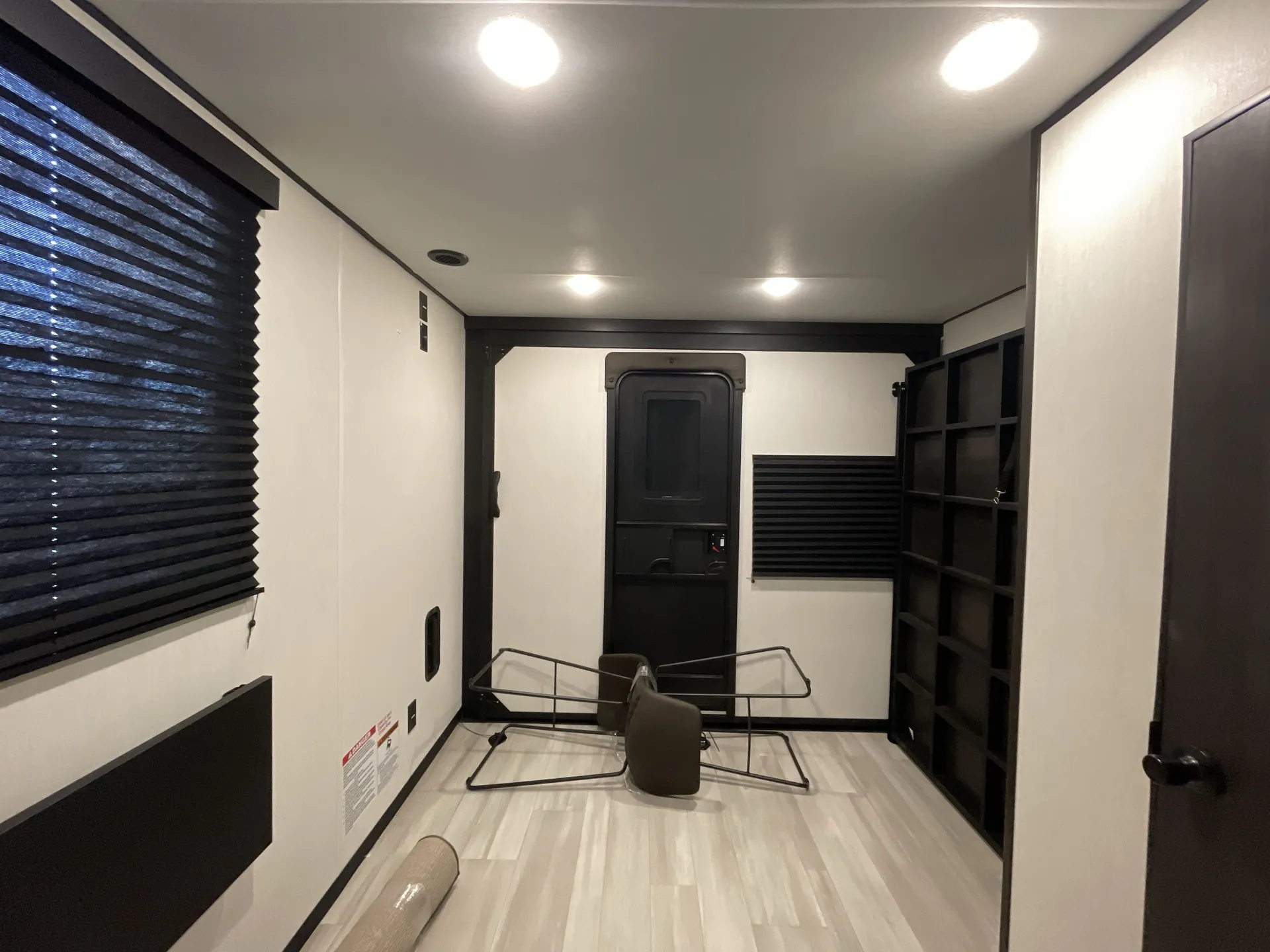 2026 Forest River Cherokee Wolf Pack 397STAY — Toy-hauler garage with open light-colored floor, fold-away seating, wall shelving, rear door, and window shade