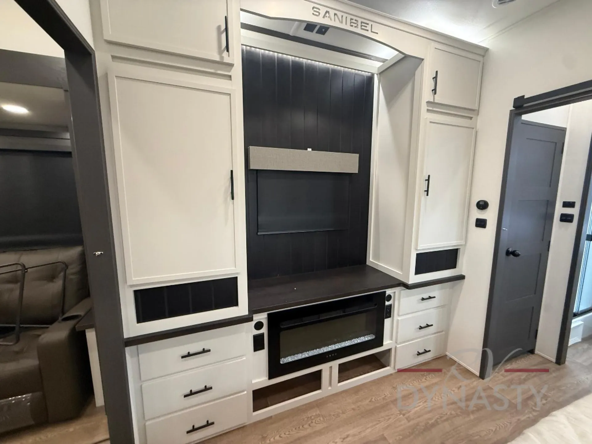 2027 Forest River Sanibel 40BUNK — Living-area entertainment center with television, electric fireplace, drawers, cabinets, and adjacent seating