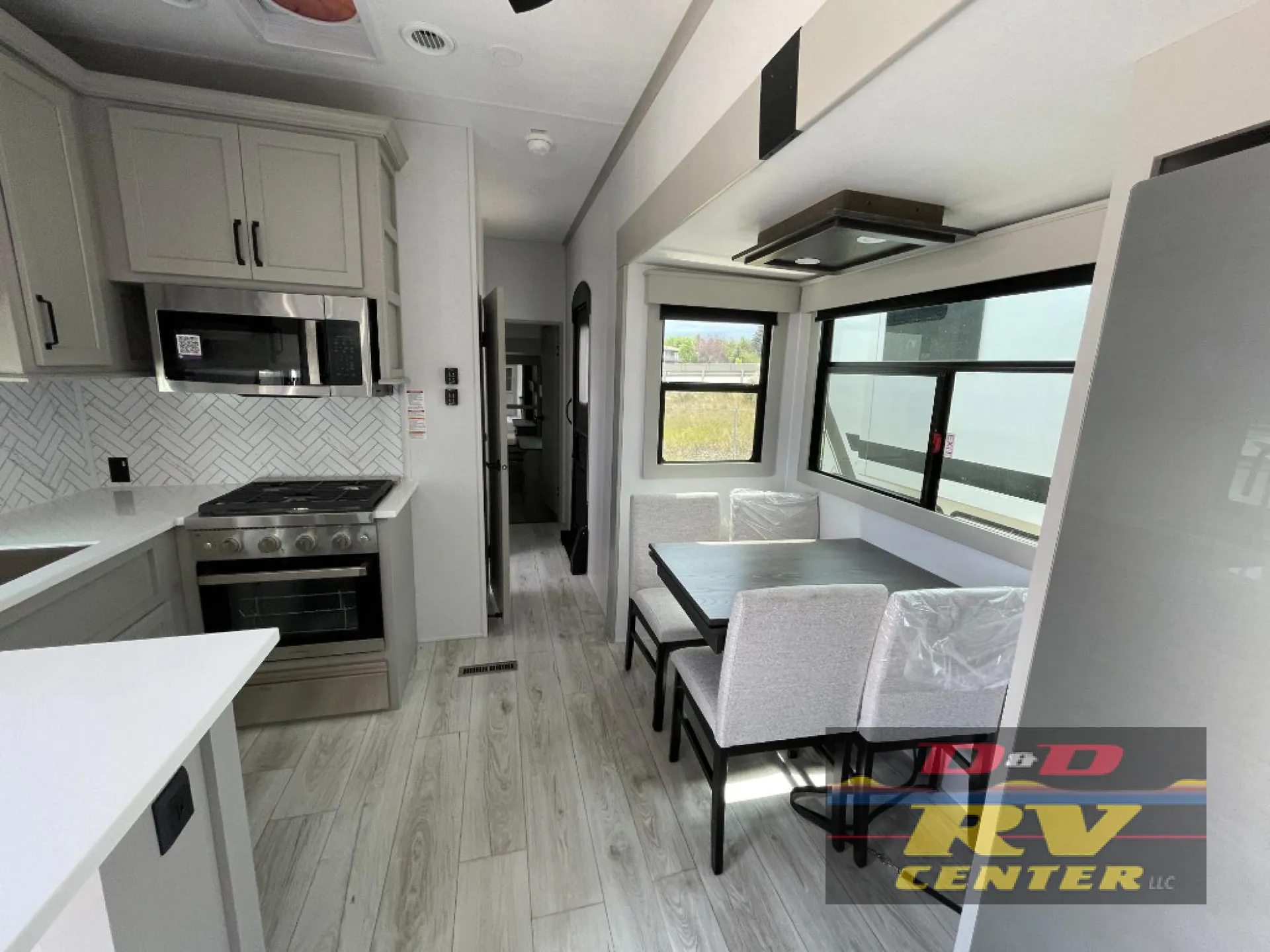 2026 Keystone Montana High Country 377FL — Four-chair dinette beside a kitchen range, microwave, counters, and large refrigerator