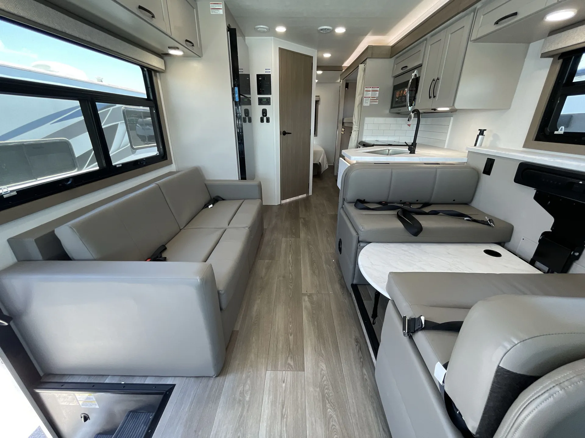 2027 Jayco Alante 29F — Living room with sofa, dinette, kitchen sink and cabinetry along a central RV aisle