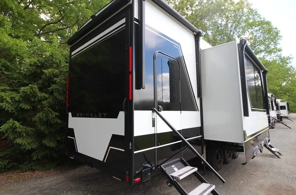 2025 Brinkley Model G 3250 — The RV exterior from the rear side, including entry door, steps, slide-outs, wheels, and body panels