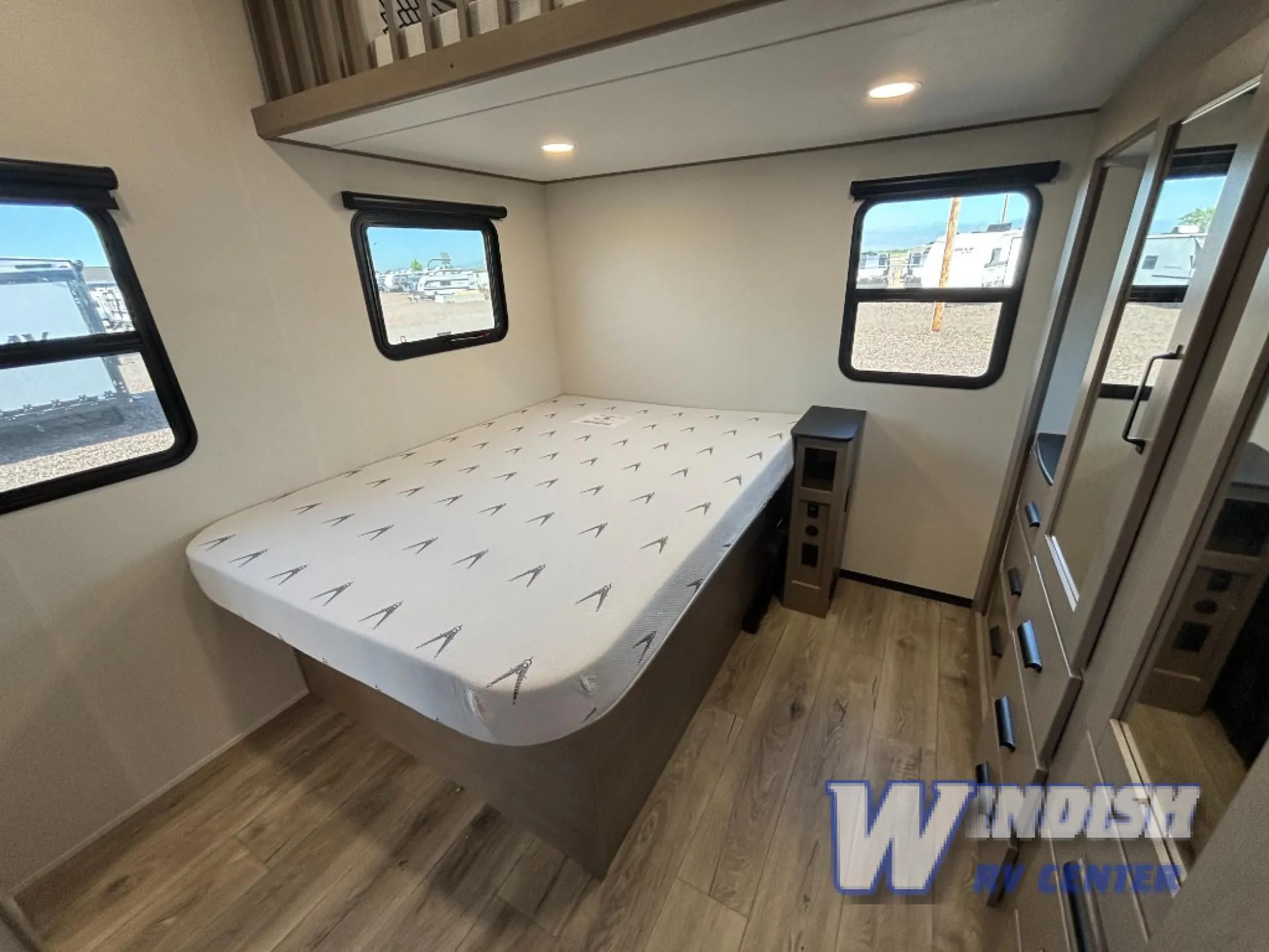 2027 Grand Design Reflection 362TBS — Main bedroom with a bed, overhead storage, windows, and mirrored wardrobe along the right wall