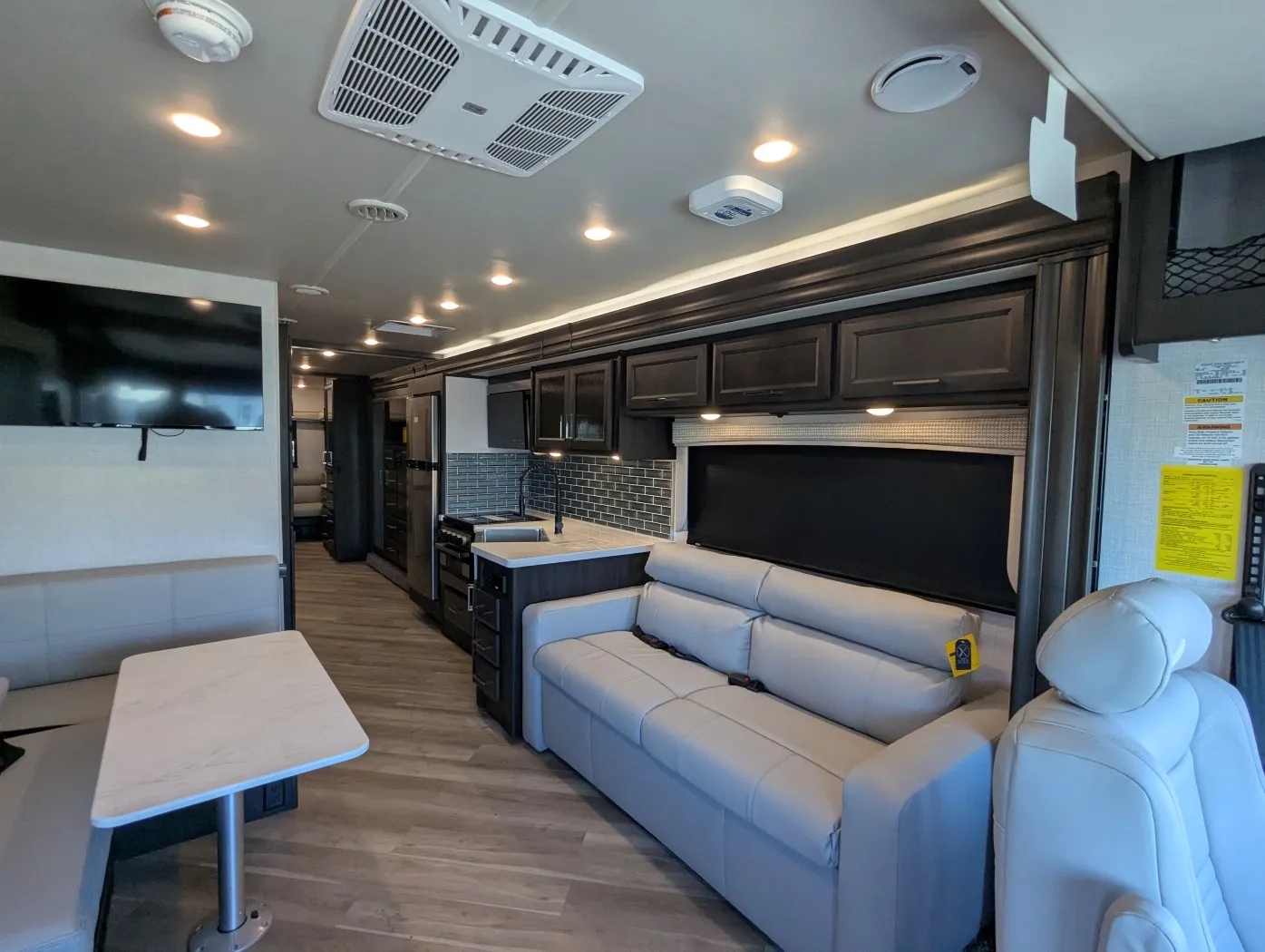 2026 Holiday Rambler Invicta 36Y — Motorhome interior overview with kitchen cabinetry and island, sofa seating, television, and dinette table