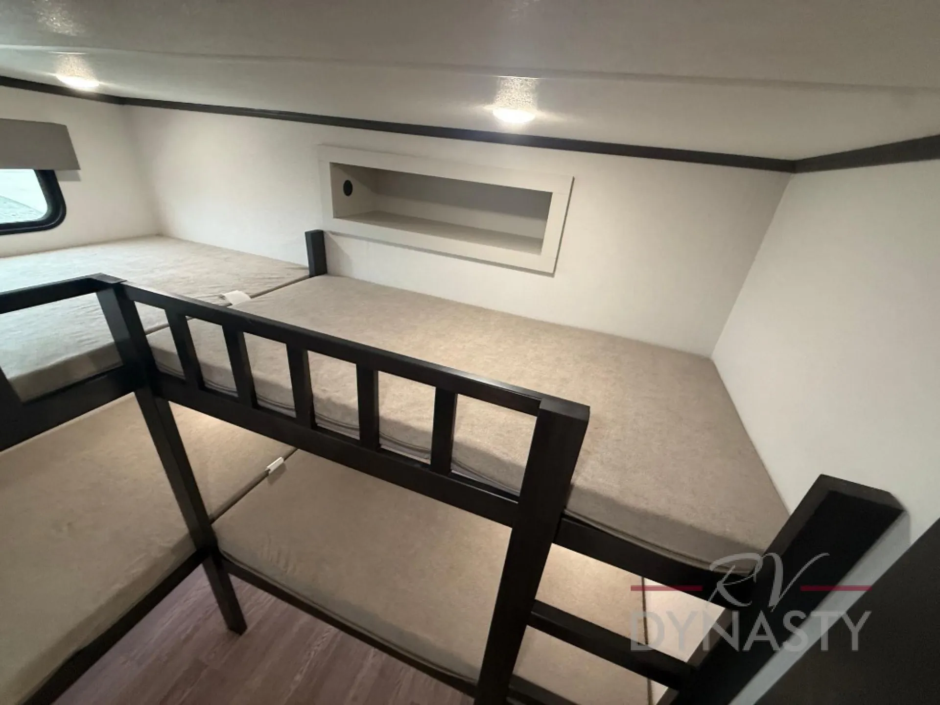 2027 Forest River Sanibel 40BUNK — Two stacked bunk mattresses with safety rails and a recessed wall shelf in a bunk sleeping area