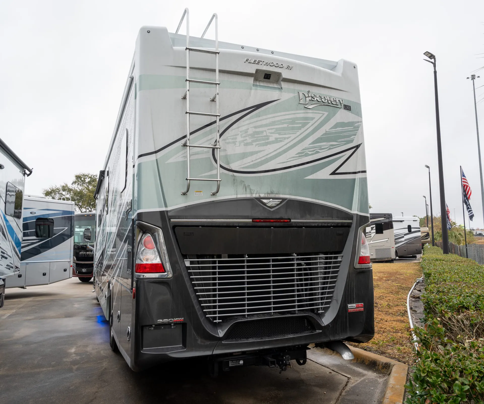 2026 Fleetwood Discovery LXE 40G — The exterior rear of a Fleetwood Discovery motorhome, including body shell, ladder, lights, grille, and hitch area