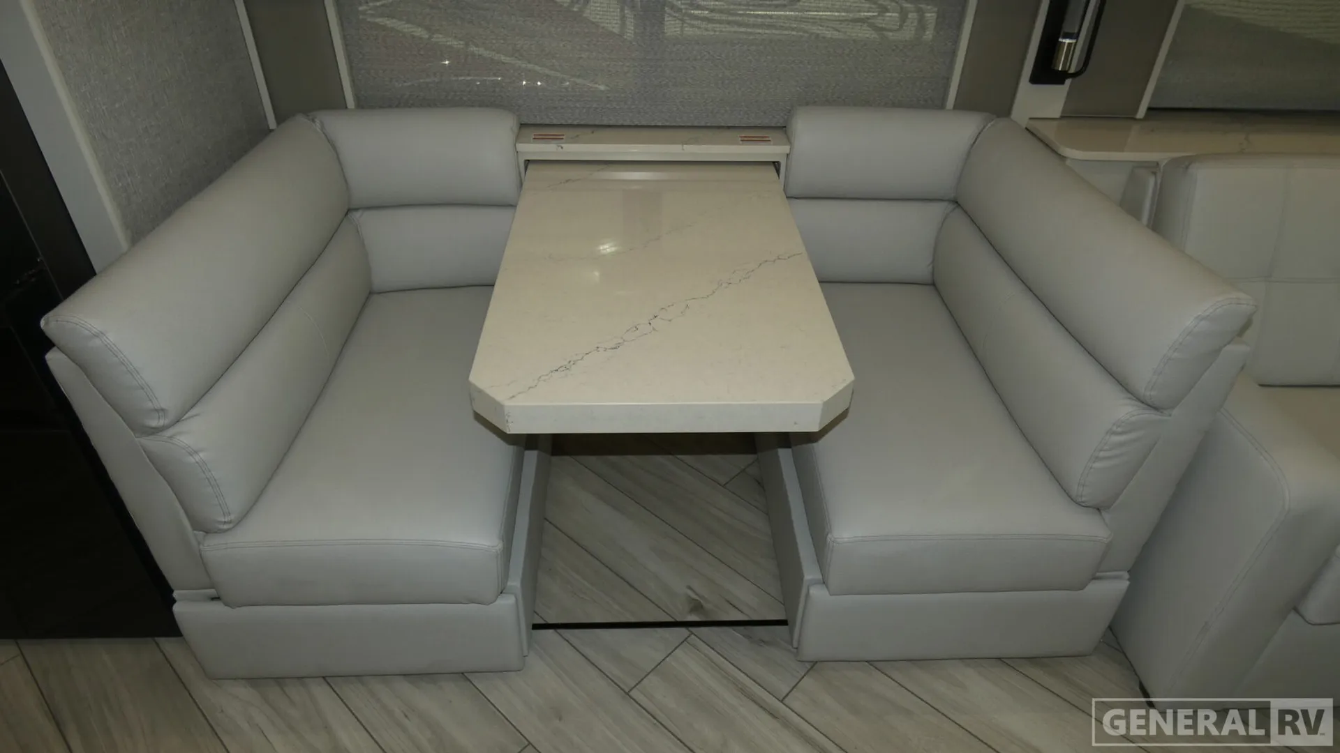 2026 American Coach American Dream 45A — Dinette table centered between opposing white bench seats, with lounge seating and overhead cabinetry visible around it