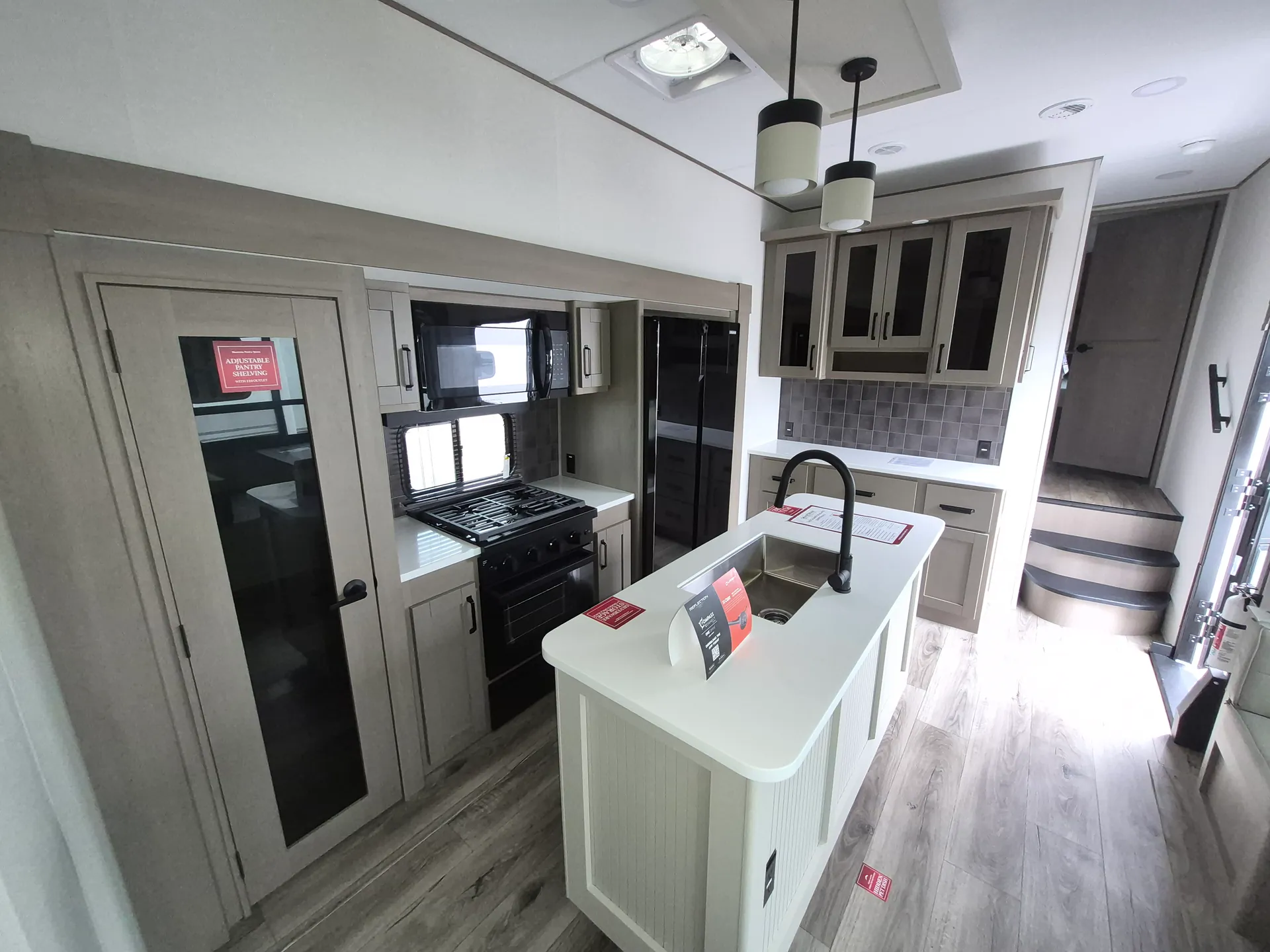 2027 Grand Design Reflection 362TBS — Fifth wheel kitchen with island sink, range, microwave, refrigerator, cabinetry, backsplash, and pantry-lined counter