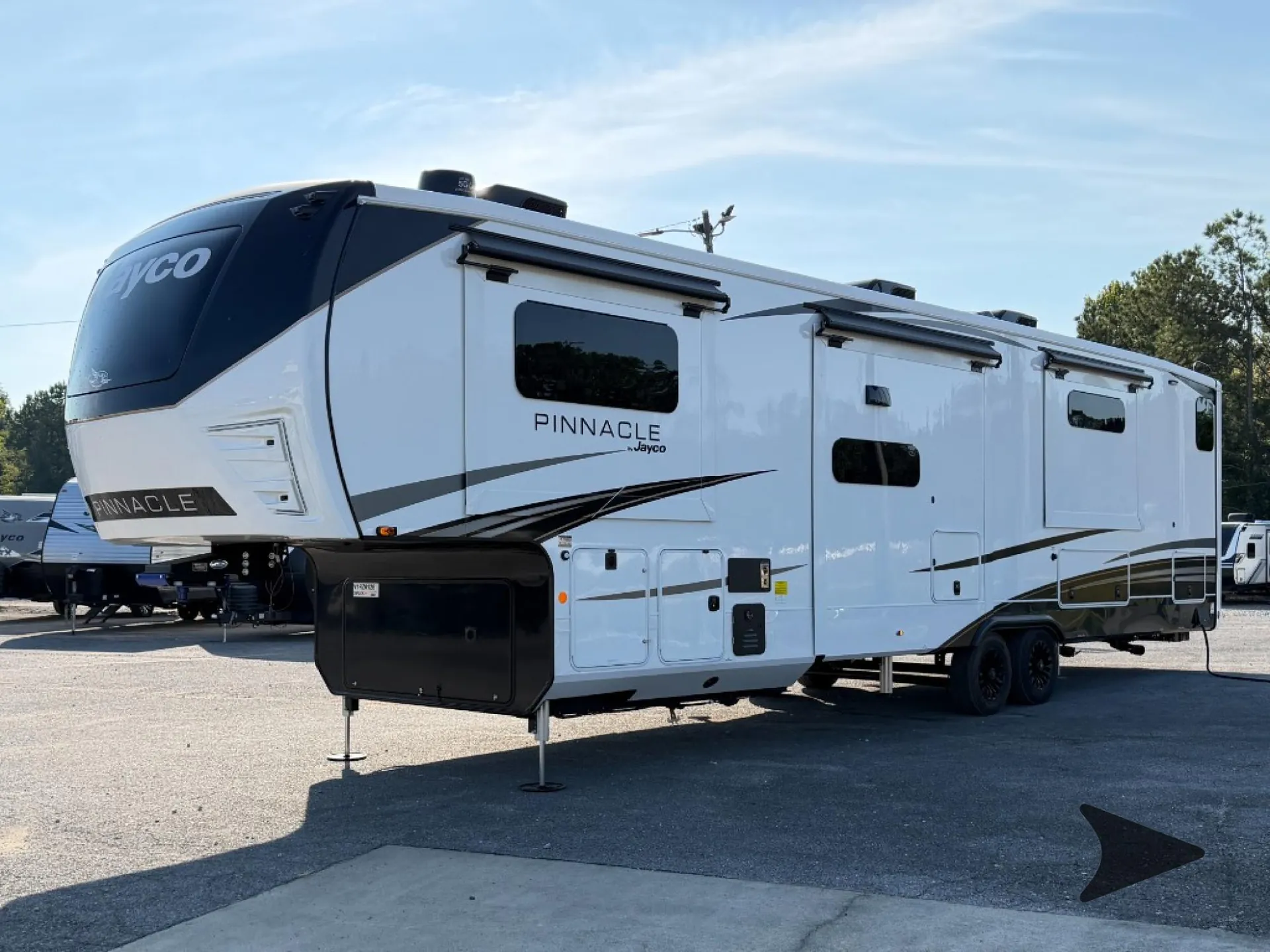 2027 Jayco Pinnacle 39FLOK — Exterior side photograph of the fifth-wheel RV showing its shell, windows, wheels, slides, and utility doors