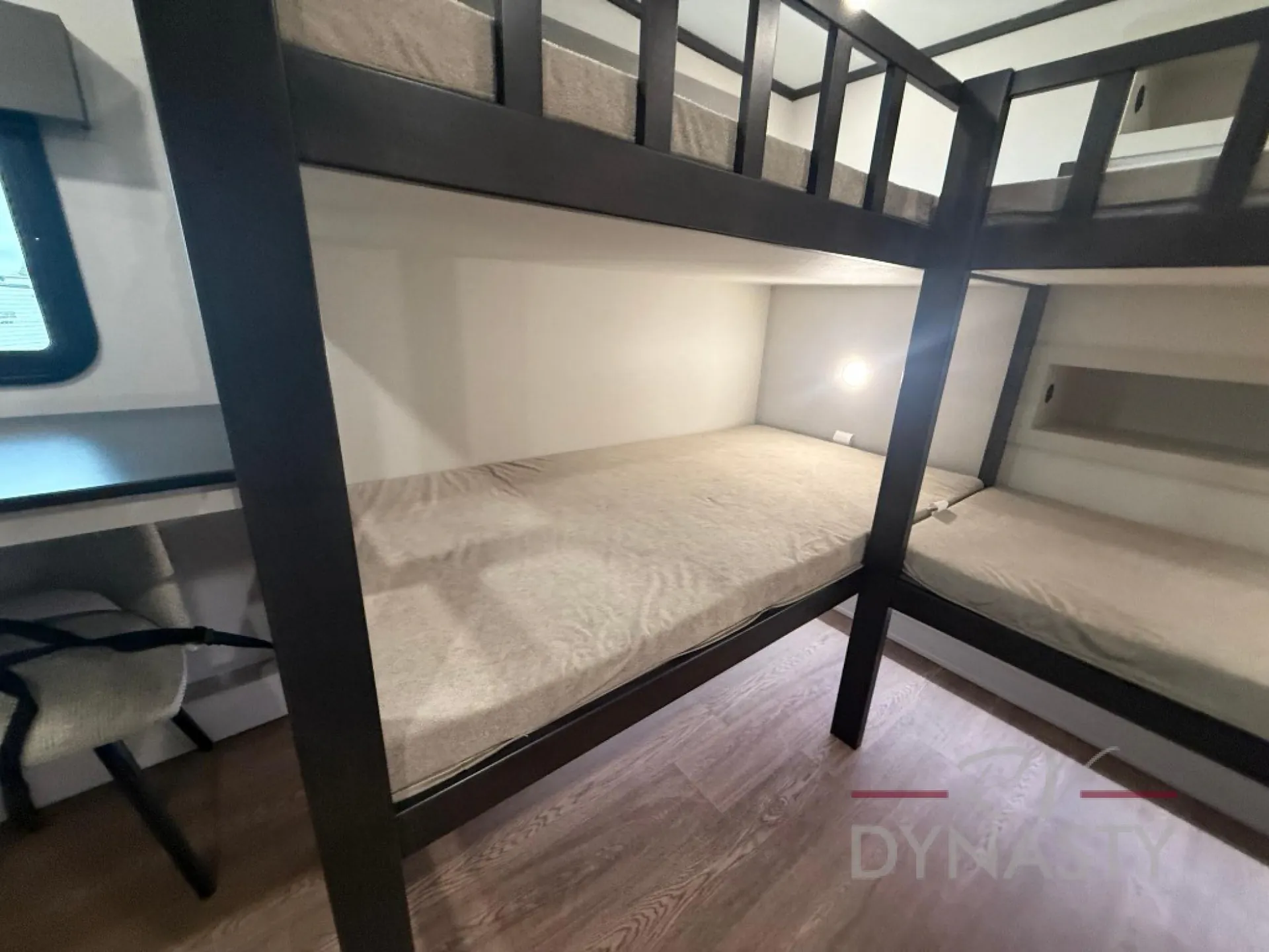 2027 Forest River Sanibel 40BUNK — Two-level bunk sleeping area with lower mattress, upper guardrails, ladder, window, and wood-look flooring