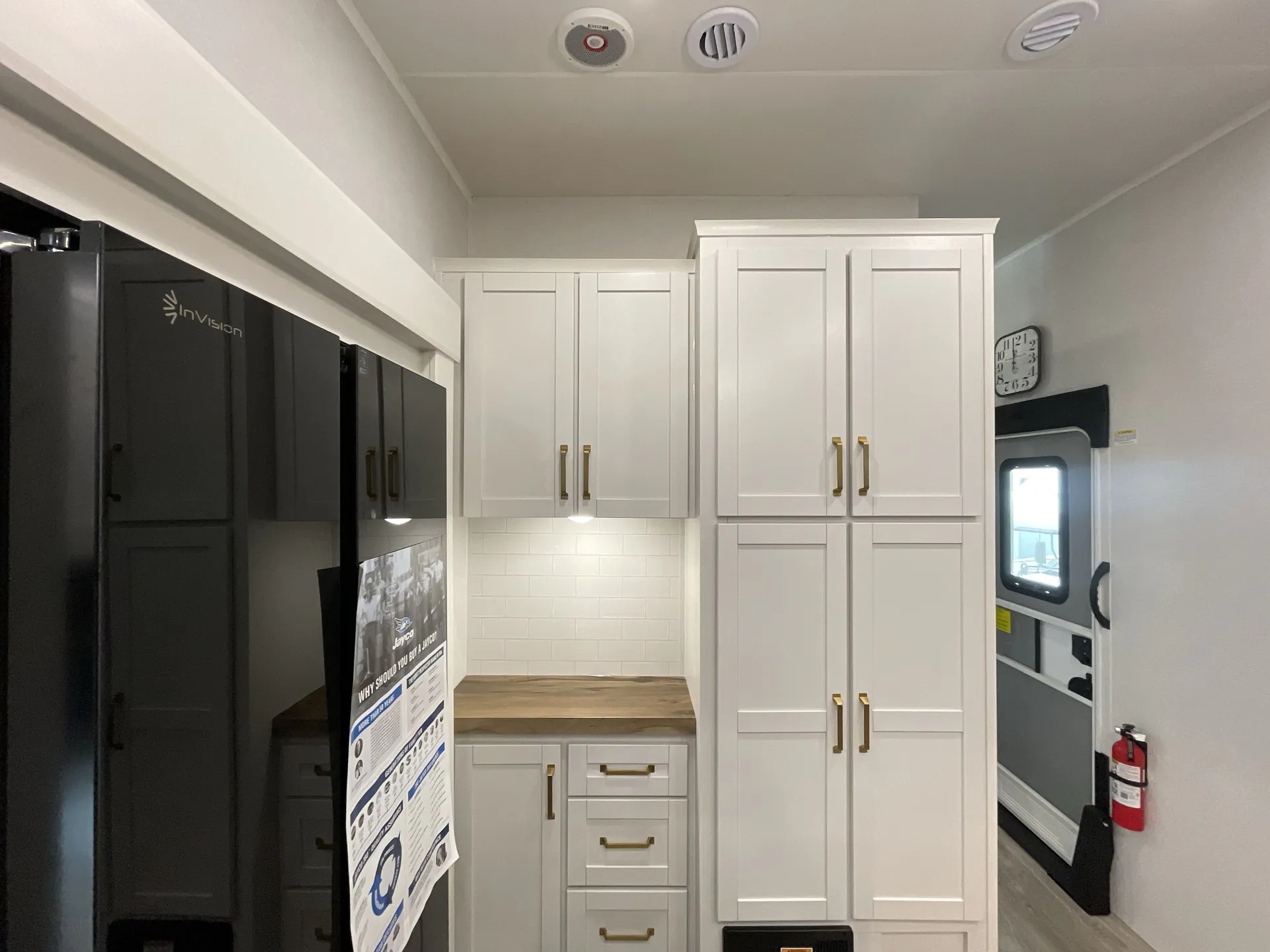 2027 Jayco Eagle 355MBQS — Kitchen storage wall with refrigerator, countertop workspace, drawers, pantry cabinets, and entryway at right