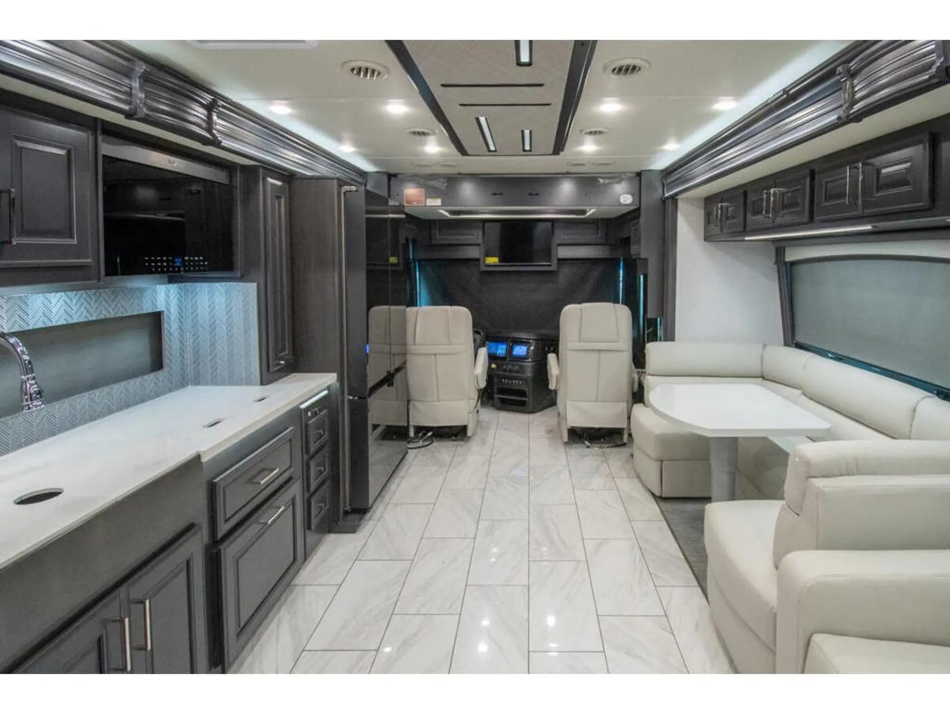 2026 Fleetwood Discovery LXE 40G — Class A motorhome overview with lounge seating, kitchen cabinetry and counters, and driver cockpit visible together