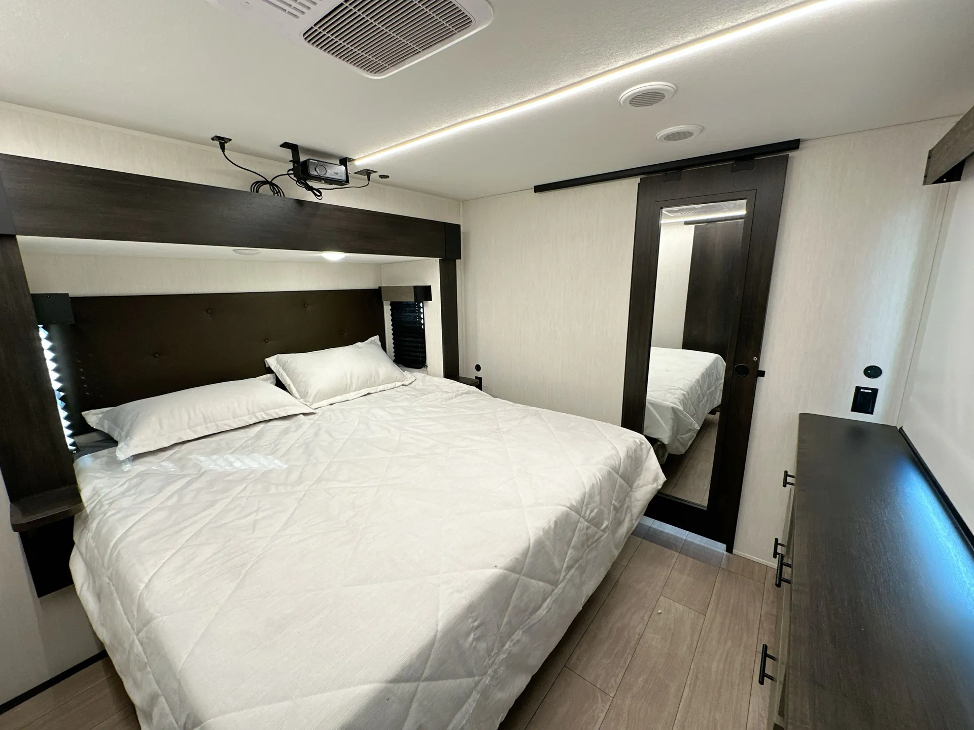 2026 Forest River Arctic Wolf 38LEAH.G — Main fifth wheel bedroom with a bed, overhead storage, mirrored wardrobe, and dresser