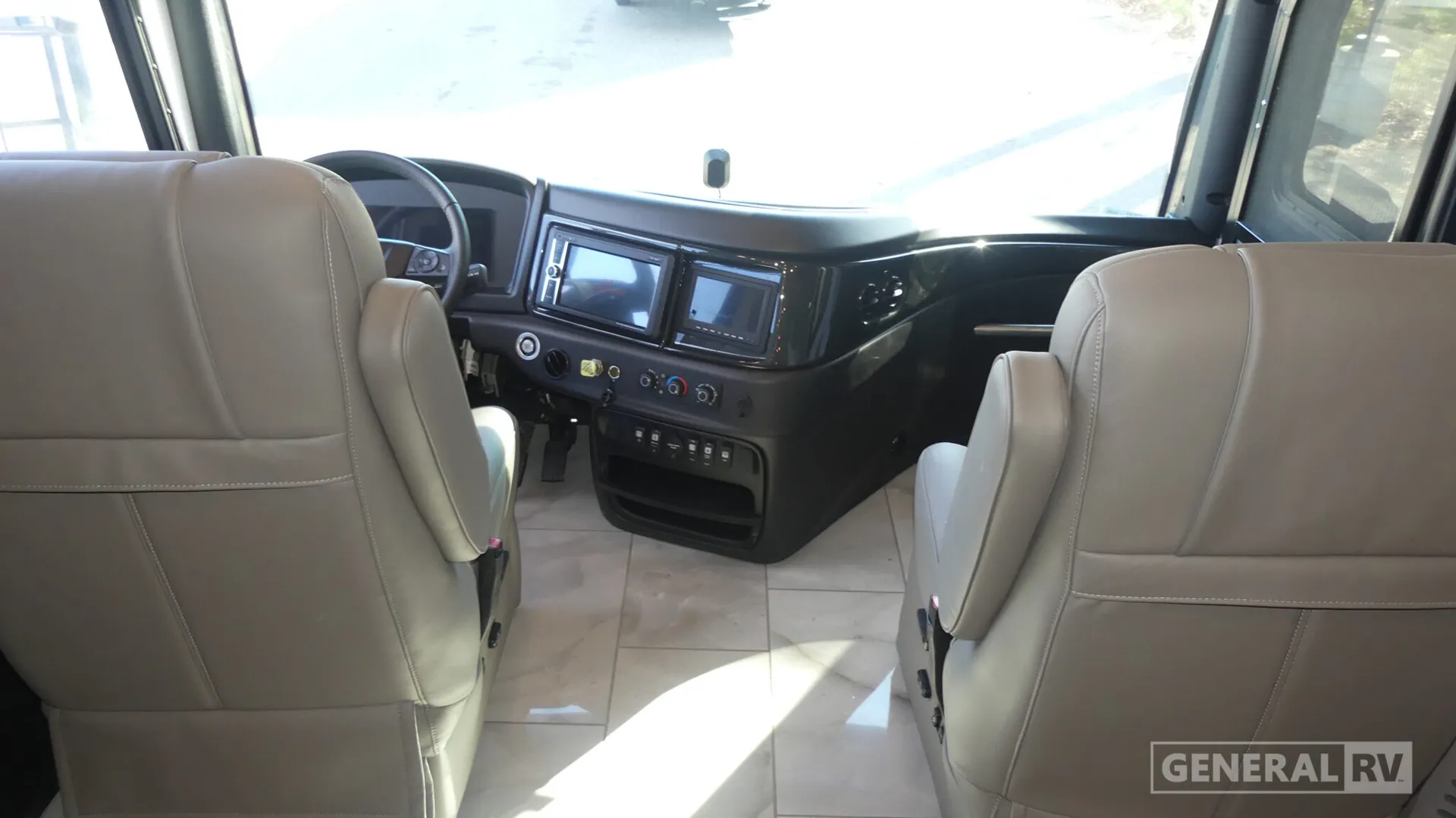 2026 Fleetwood Discovery LXE 40G — Class A cockpit with steering wheel, driver and passenger seats, dashboard screens, climate controls, and windshield