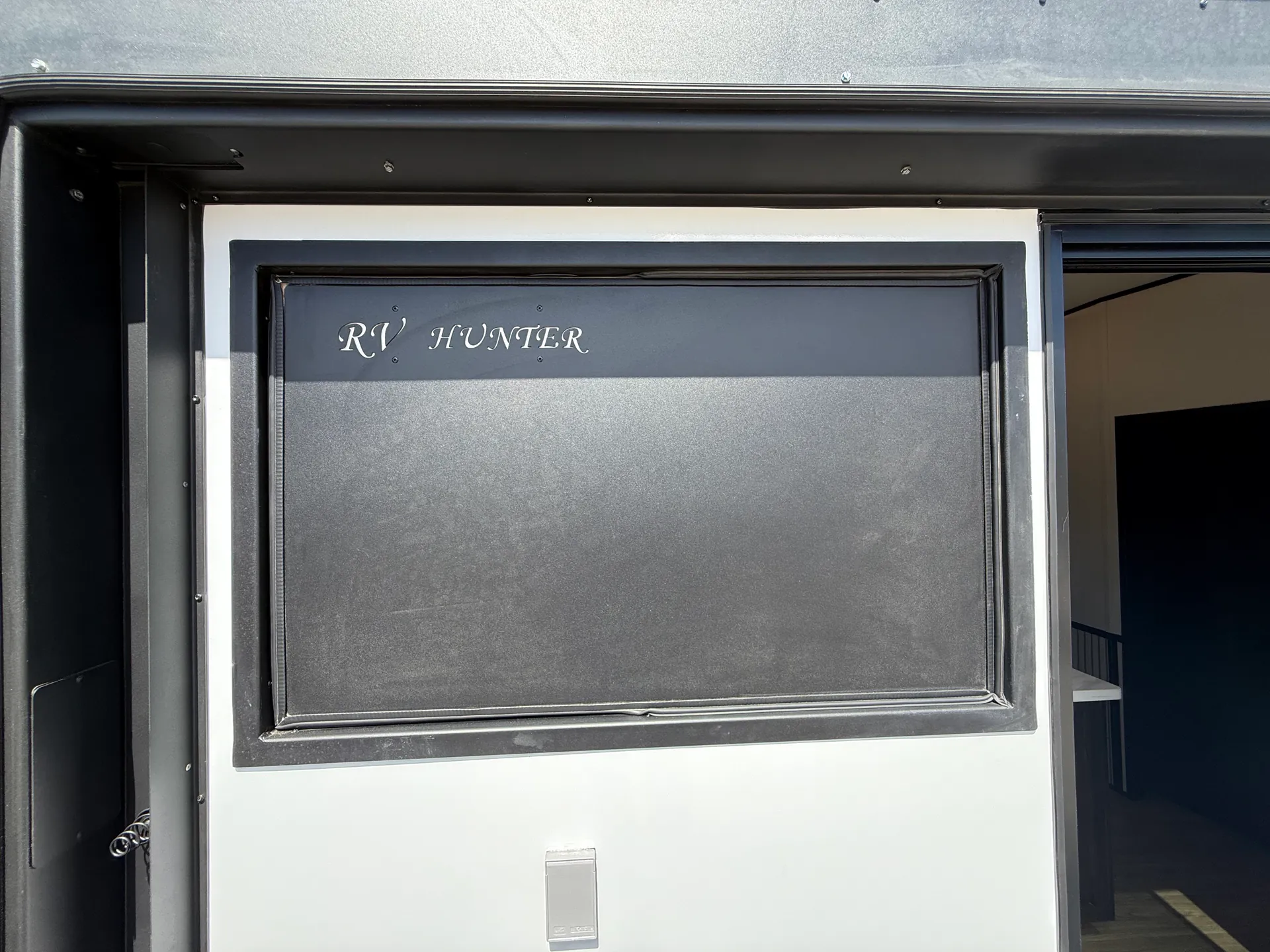 2027 Forest River Sabre 38RVHUNTER — Close exterior photograph of the RV Hunter-branded entry door and exterior wall