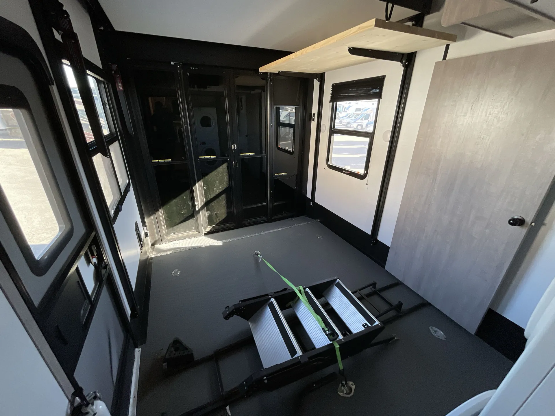 2023 Dutchmen Voltage 4225 — Toy-hauler garage with broad black cargo floor, loading aisle, tie-down hardware, windows, and fold-away platform equipment