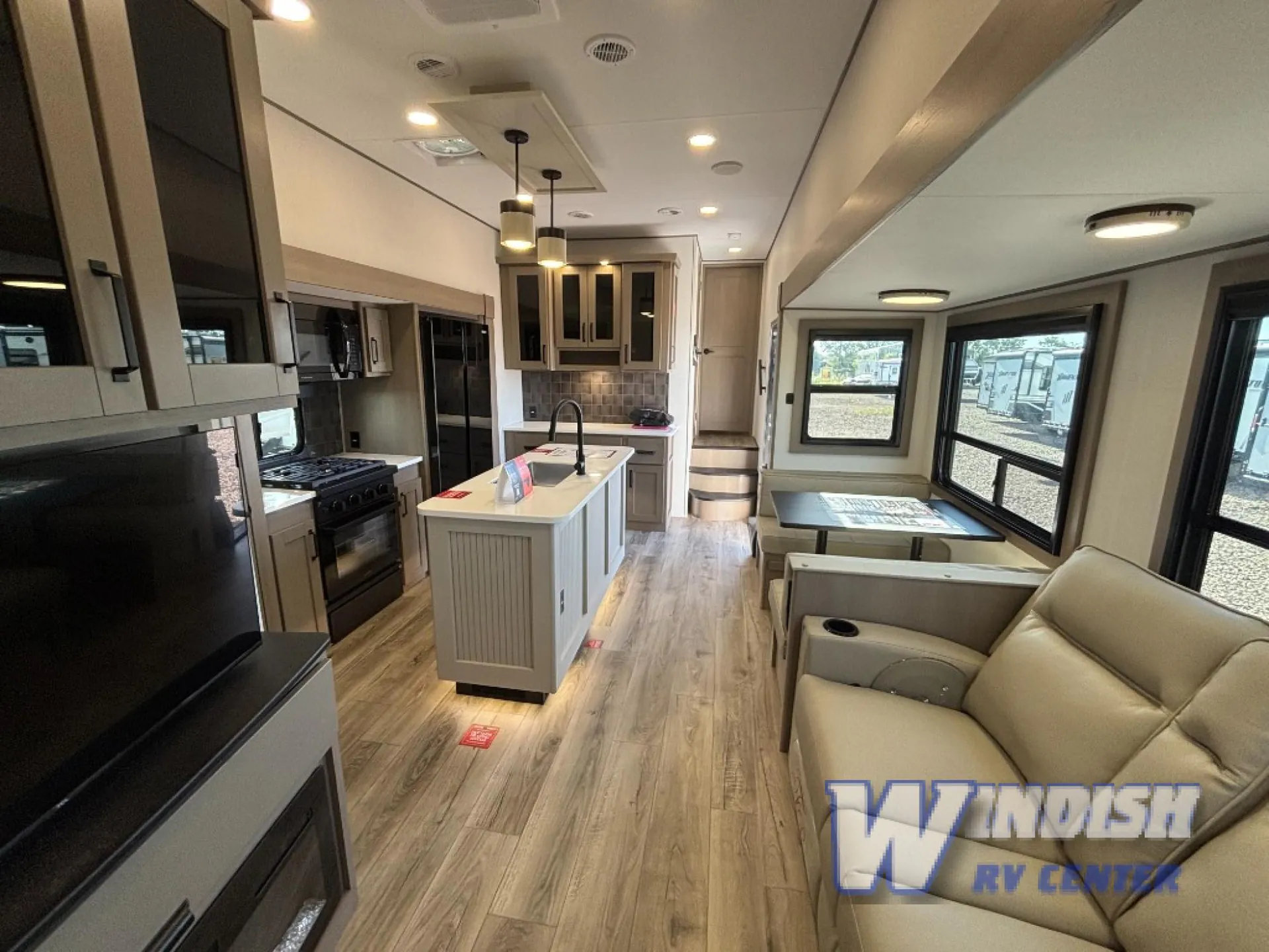 2027 Grand Design Reflection 362TBS — Fifth-wheel interior overview with kitchen island, dinette, reclining sofa, refrigerator, and entertainment center