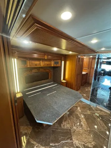 2016 Newmar Dutch Star 4369 — Main bedroom with a large upholstered bed, overhead cabinetry, and polished wood storage surrounding the sleeping area