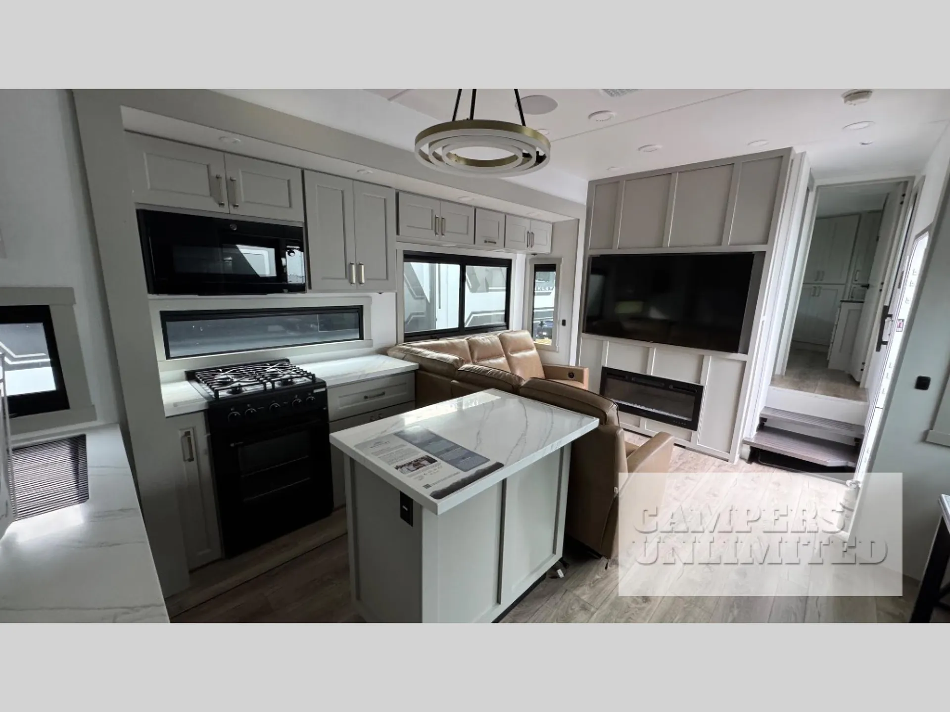 2026 Brinkley Model G 3950 — Kitchen island, range, microwave, refrigerator, and cabinetry open toward a sofa and entertainment wall