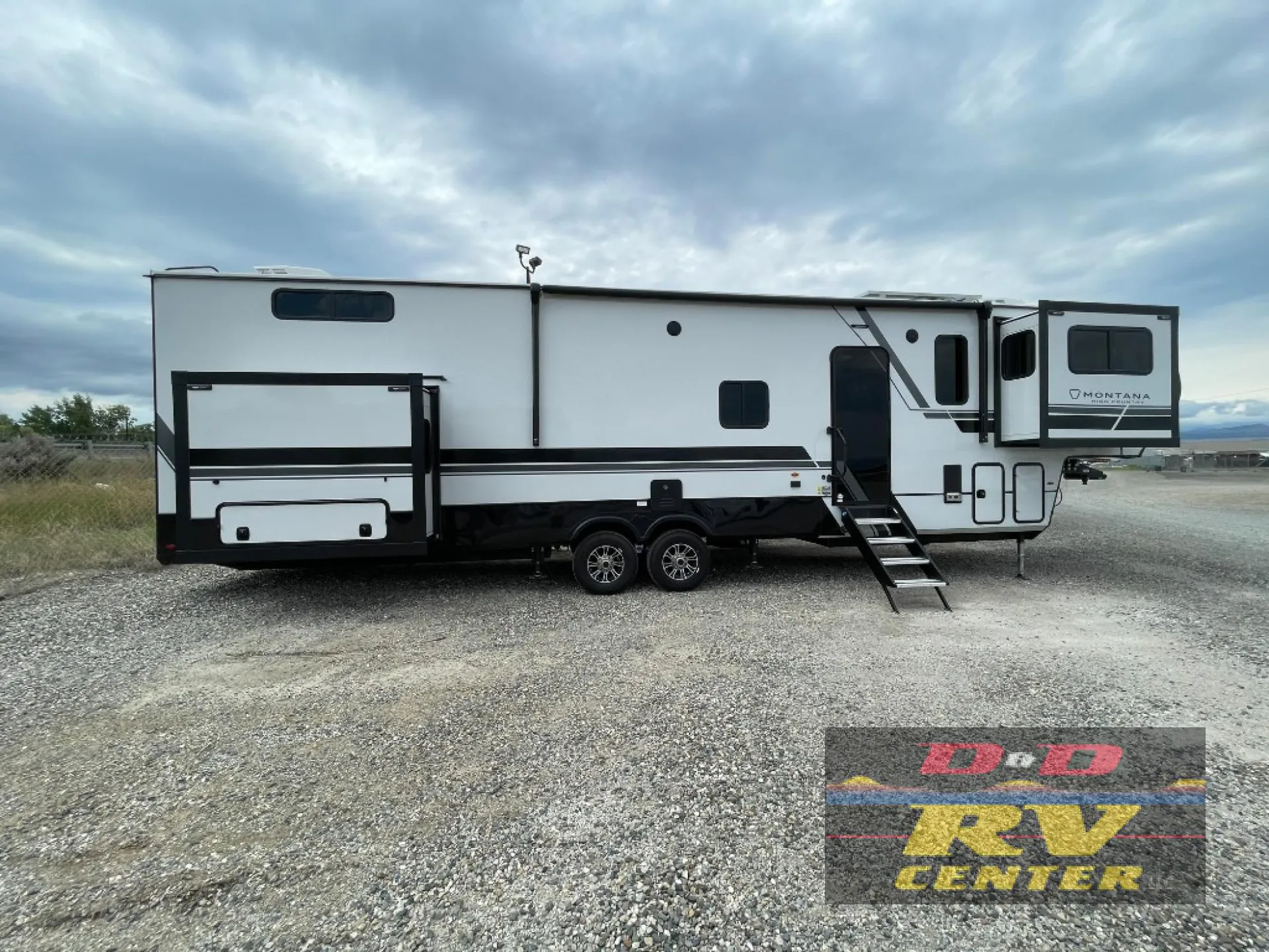 2026 Keystone Montana High Country 377FL — Wide exterior side photograph visibly shows the complete fifth-wheel RV, wheels, slide-outs, entry steps, and hitch