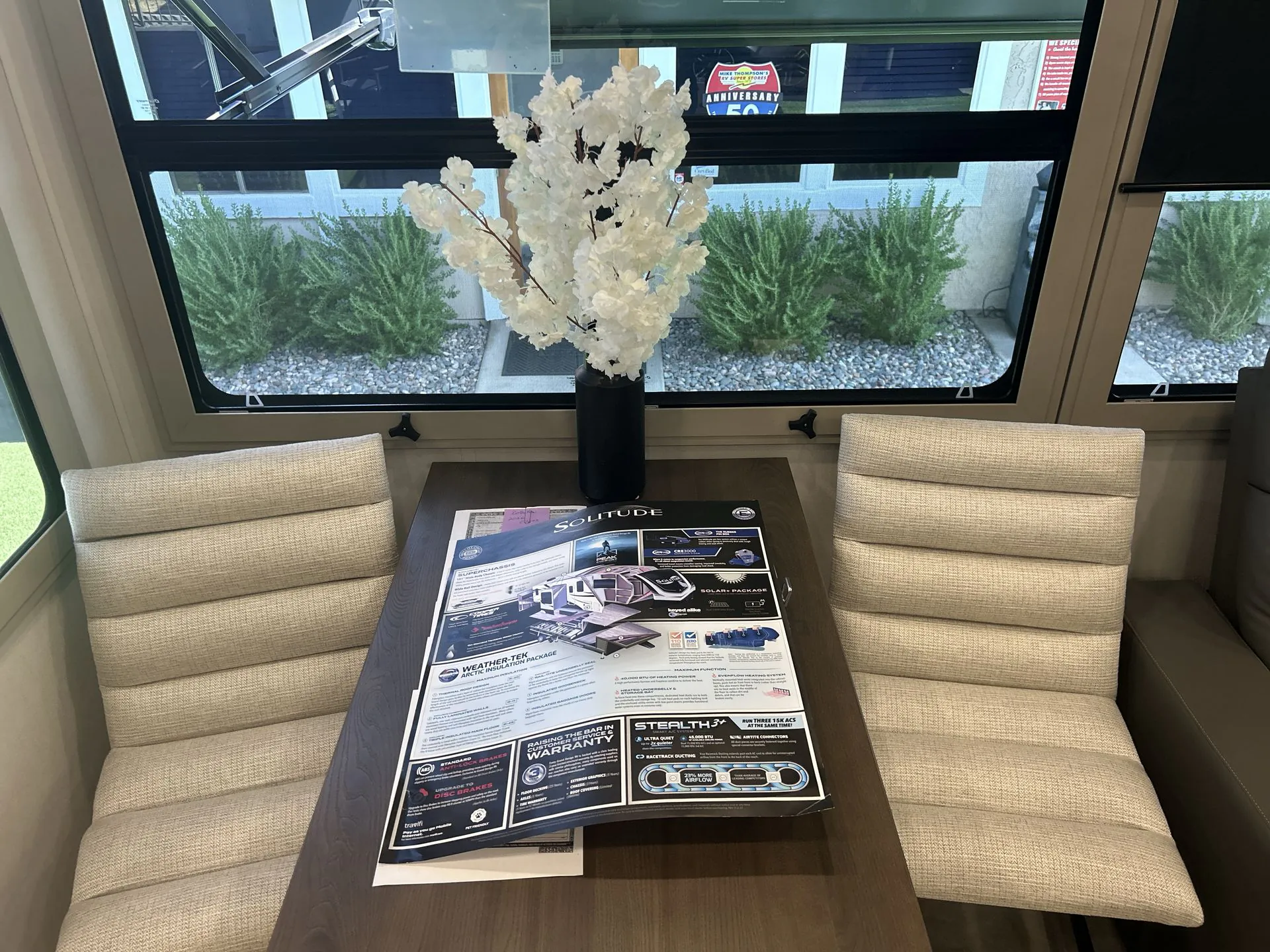 2026 Grand Design Solitude 391DL — Fifth wheel dining area with four upholstered chairs, rectangular table, vase, and large windows