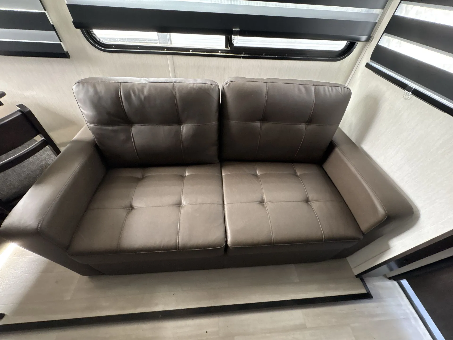 2026 Forest River Cherokee Wolf Pack 397STAY — Travel trailer reclining sofa beneath two windows with layered roller shades