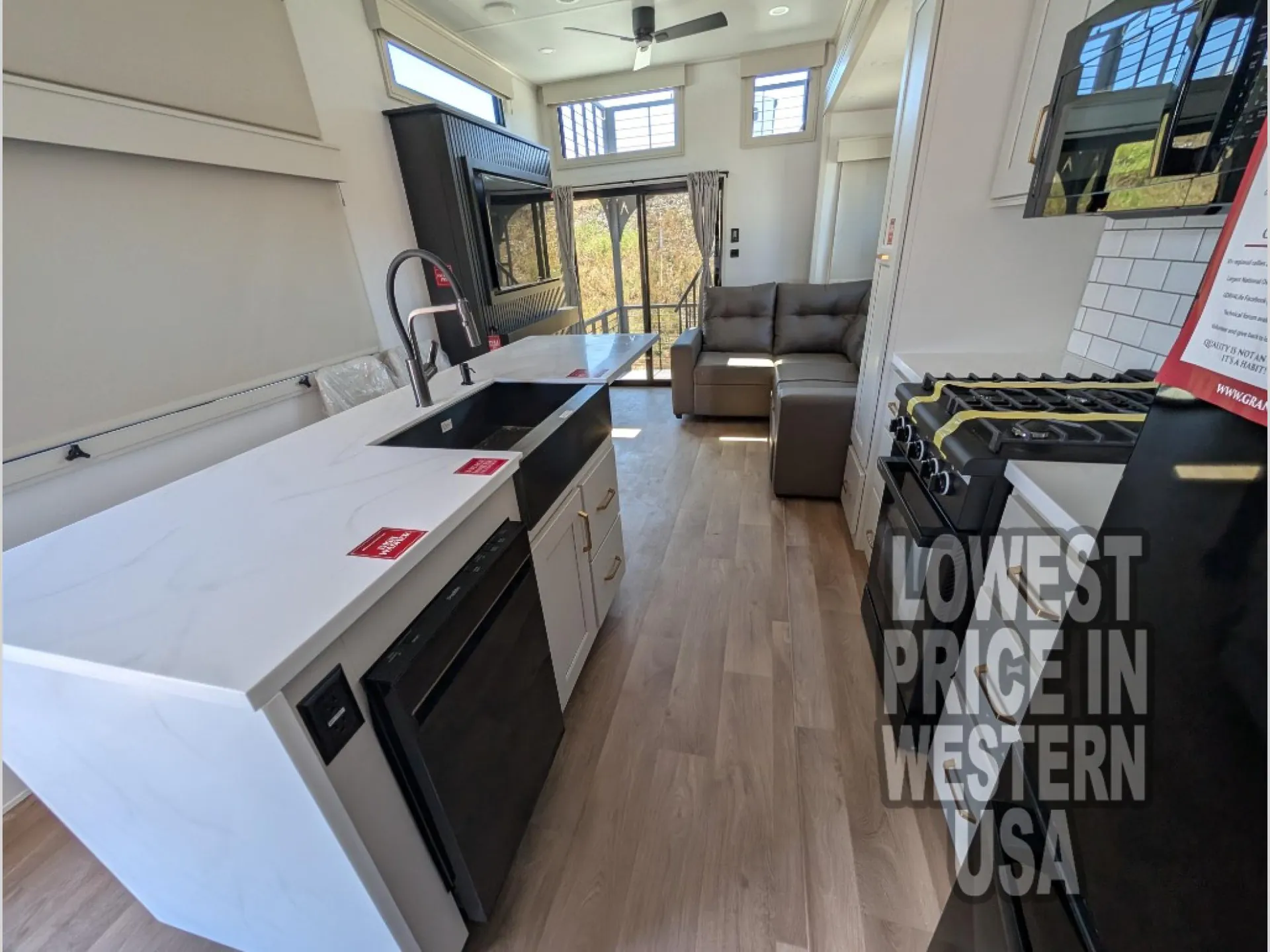 2026 Grand Design Foundation 42GD — Kitchen island, sink, dishwasher, range, and counters lead toward a sectional lounge with an entertainment cabinet