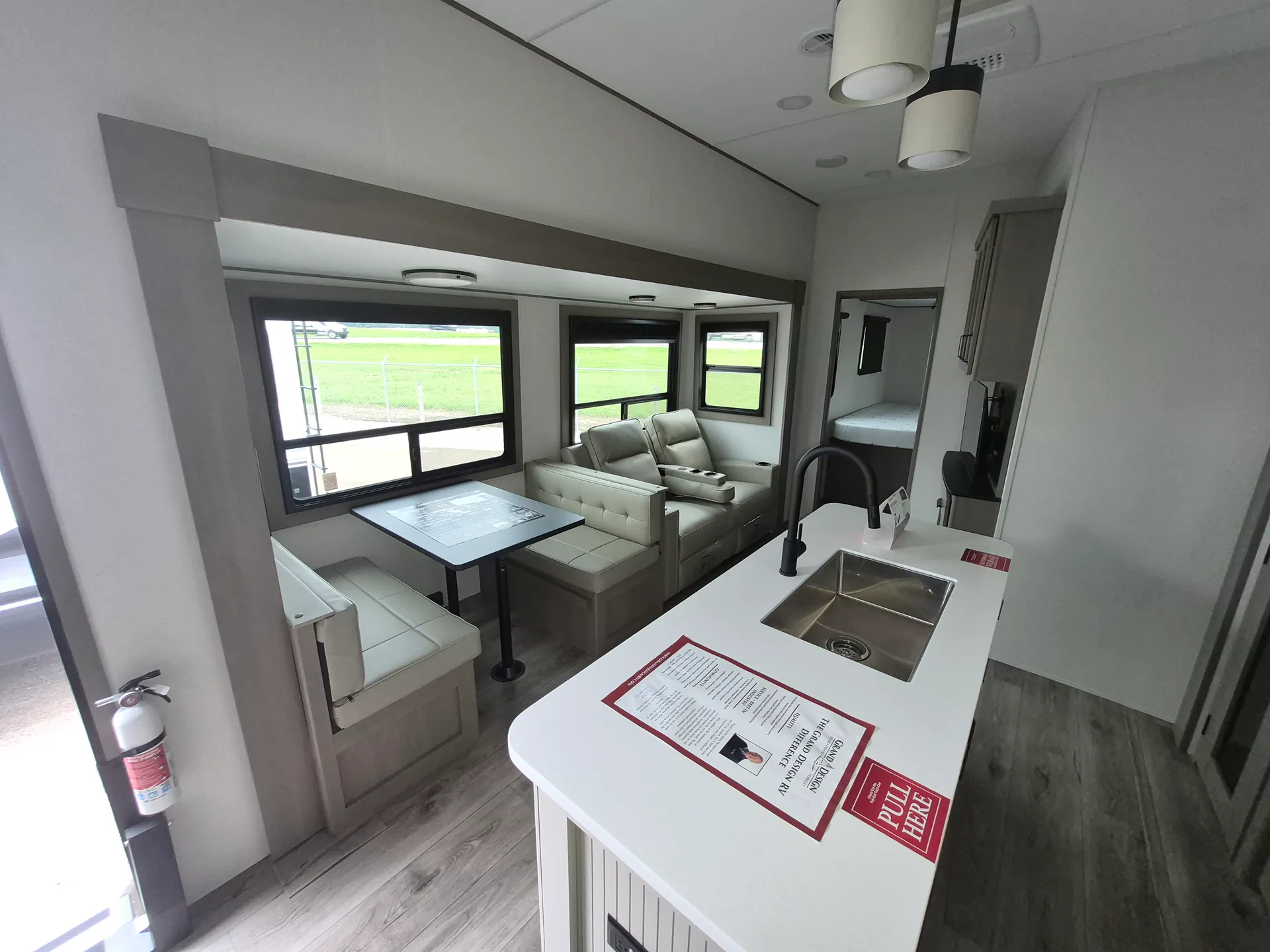 2027 Grand Design Reflection 362TBS — Fifth wheel lounge with dual recliners and dinette beside a kitchen island sink, with a bedroom doorway beyond